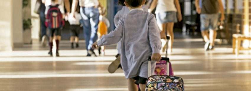 niño con baby y mochila en el colegio corriendo para llegar al aula