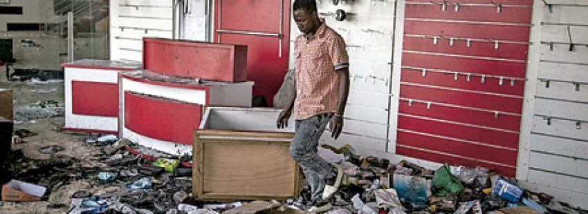 joven en una tienda destrozada por la violencia postelectoral tras los comicios de diciembre 2016 cuando ganó el opositor frente a la dictadura