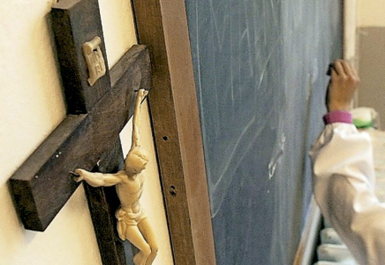 crucifijo en el aula en una escuela una niña escribe en la pizarra
