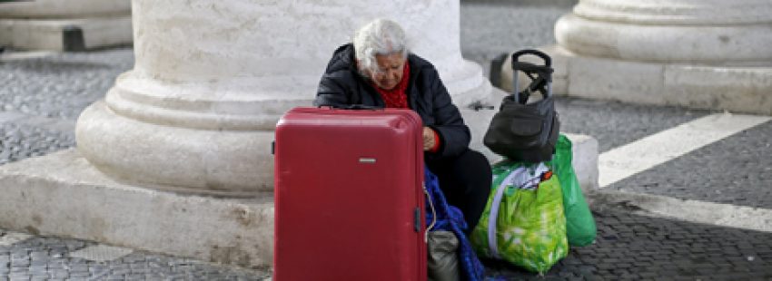 mujer sin techo con maleta y bolsas espera a otra persona en la Plaza de San Pedro del Vaticano