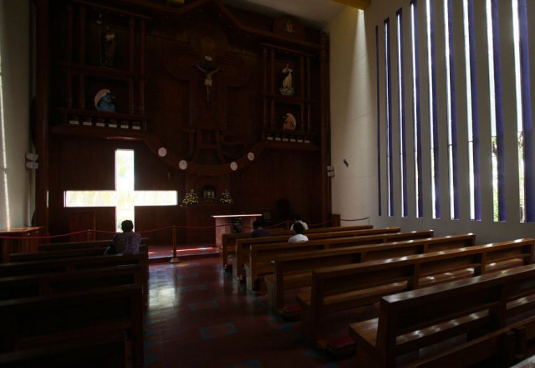 Una iglesia casi vacía en la que algunas personas rezan archivo