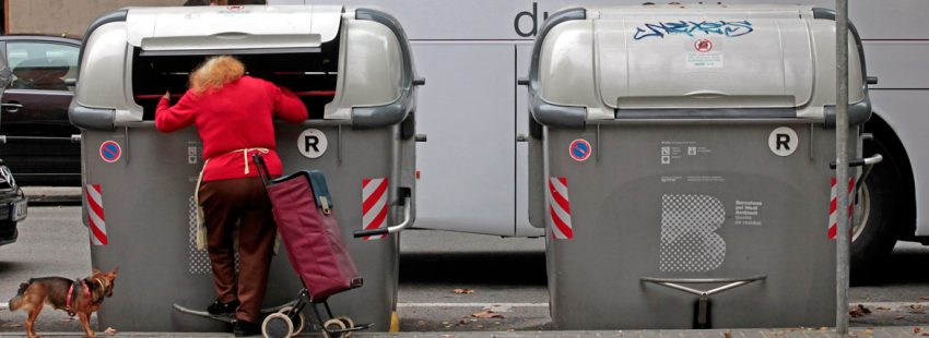 Una mujer pobre busca comida en un contenedor de basura en Barcelona