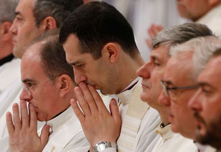 grupo de sacerdotes en una celebración misa rezando en silencio