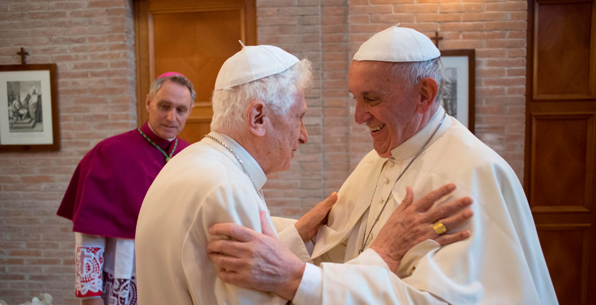 Benedicto XVI y Francisco se saludan ante la mirada de George Gänswein papas