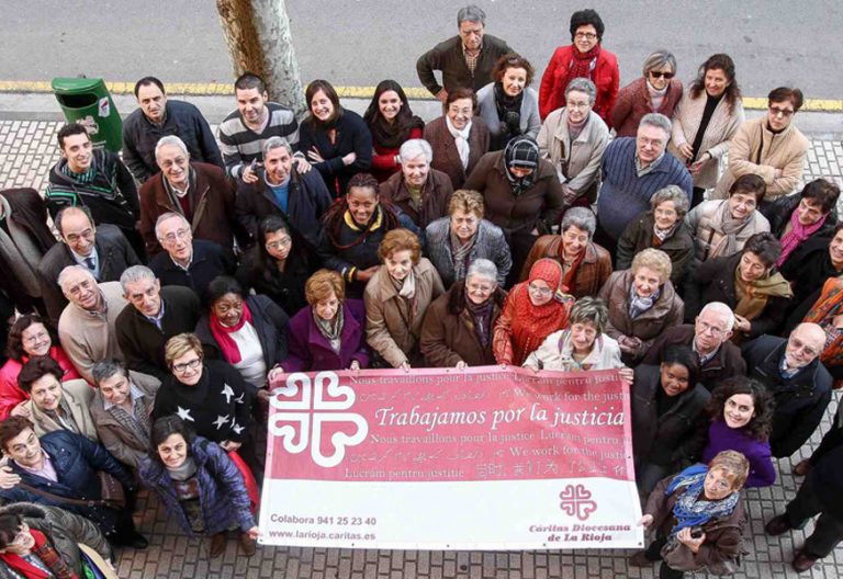 Un grupo de voluntarios de Cáritas de La Rioja sostiene una pancarta con el lema "Trabajamos