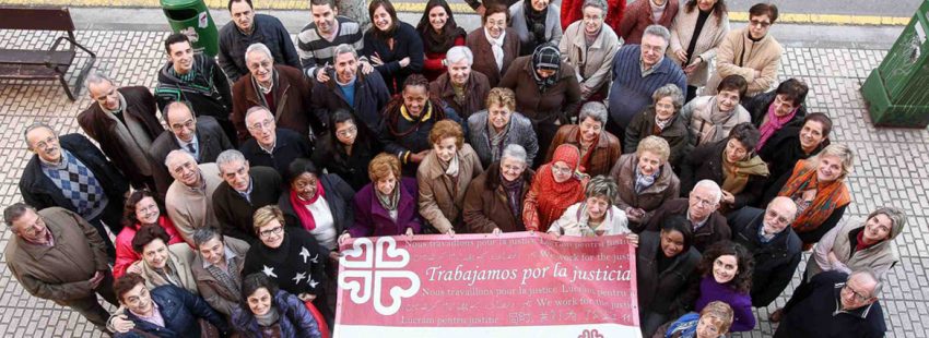 Un grupo de voluntarios de Cáritas de La Rioja sostiene una pancarta con el lema "Trabajamos
