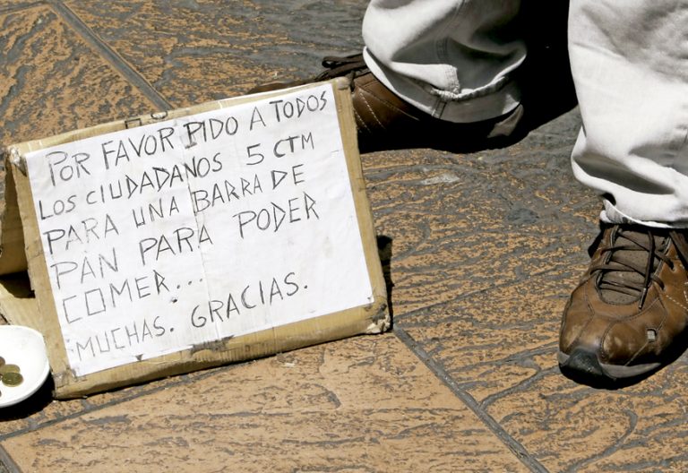 hombre pidiendo limosna en la calle con un cartel