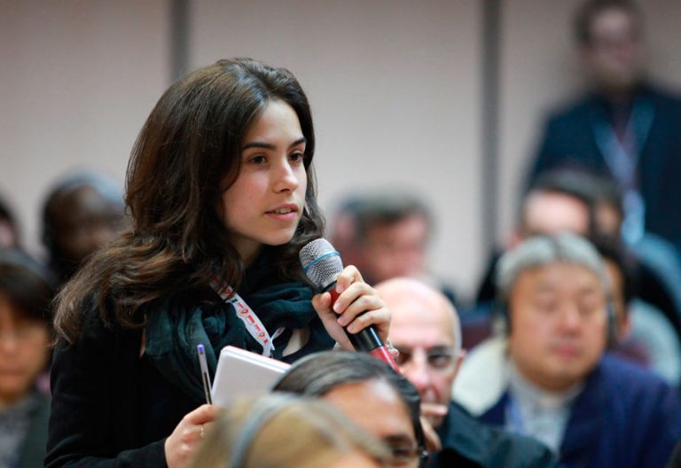 chica joven con micrófono en la mano habla en una asamblea eclesial