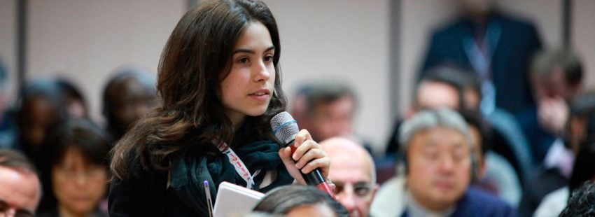 chica joven con micrófono en la mano habla en una asamblea eclesial