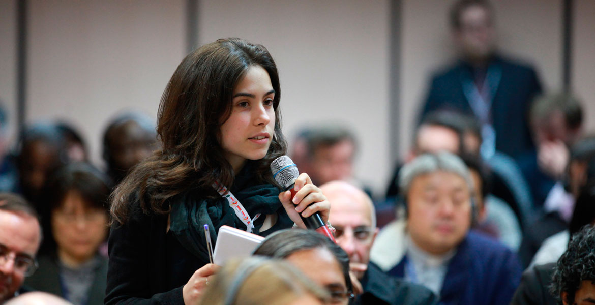 chica joven con micrófono en la mano habla en una asamblea eclesial