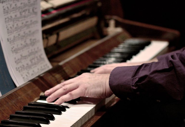pianista manos de un músico tocando el piano con partitura