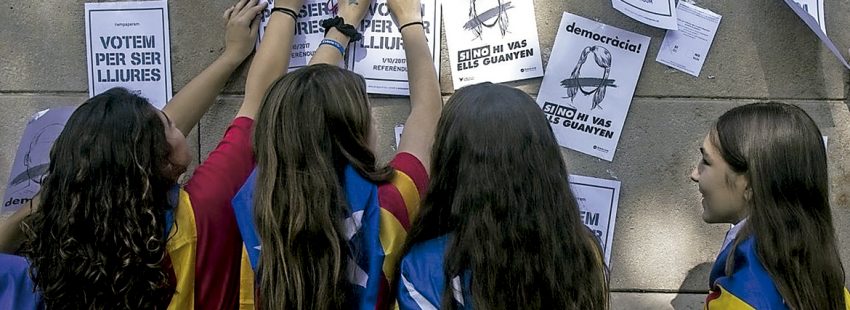 niñas jóvenes en Cataluña con bandera estelada independentista colgando carteles de propaganda