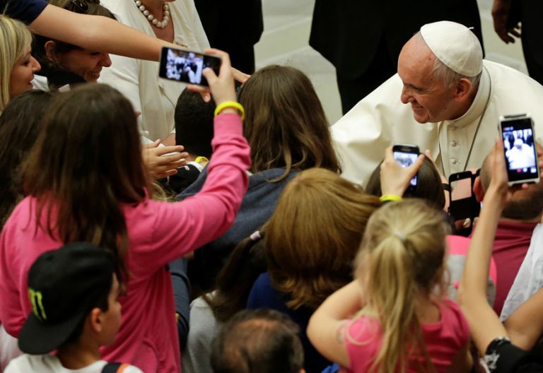 papa Francisco con un grupo de jóvenes que les hacen fotos