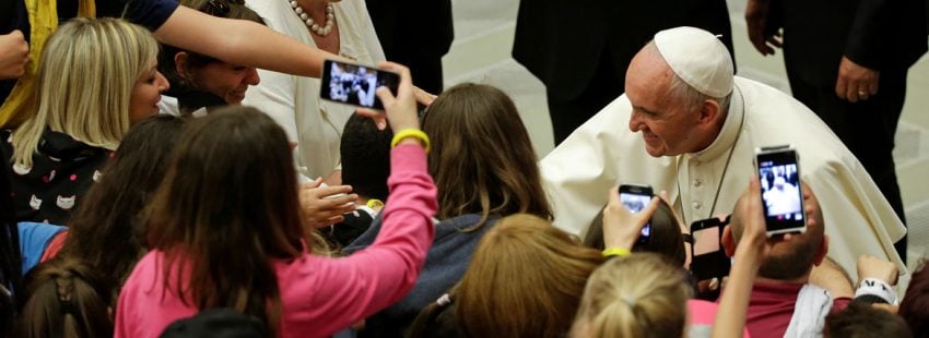 papa Francisco con un grupo de jóvenes que les hacen fotos