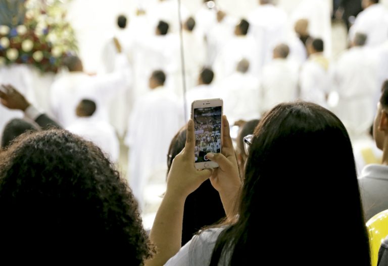 jóvenes en misa haciendo una foto con el teléfono móvil