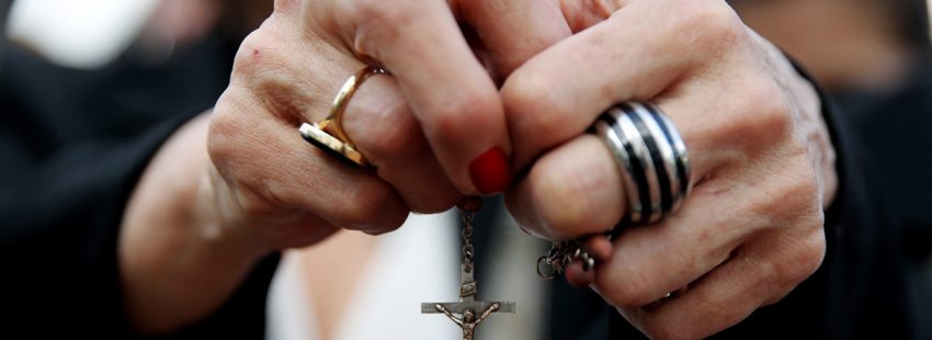 manos de mujer con un rosario rezando