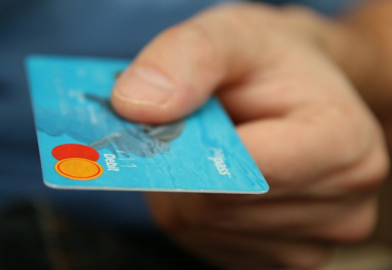 una mano sostiene una tarjeta de crédito para hacer una compra y pagar