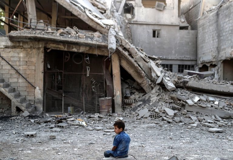 Un niño junto a una mezquita devastada por la guerra en Siria