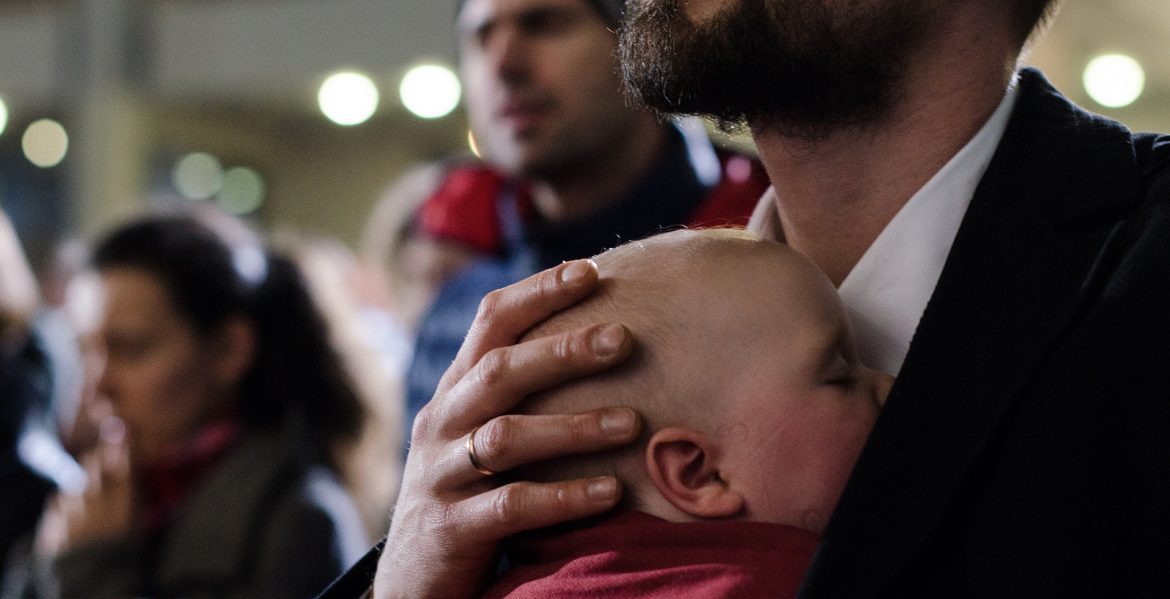Un padre con su hijo bebé participan en una eucaristía en Cracovia/JMJ