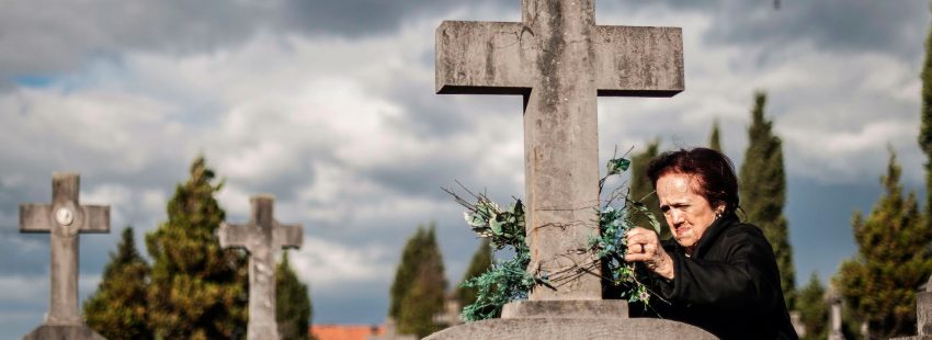 Mujer pone flores en un cementerio