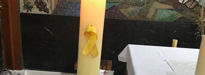 Lazo amarillo en un cirio del altar de la parroquia de comarruga