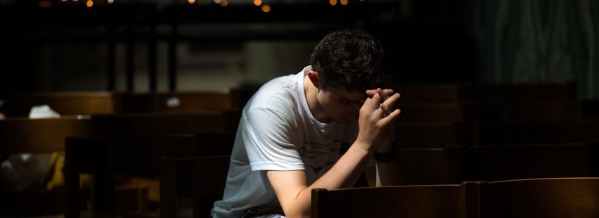 Un joven ora en una iglesia