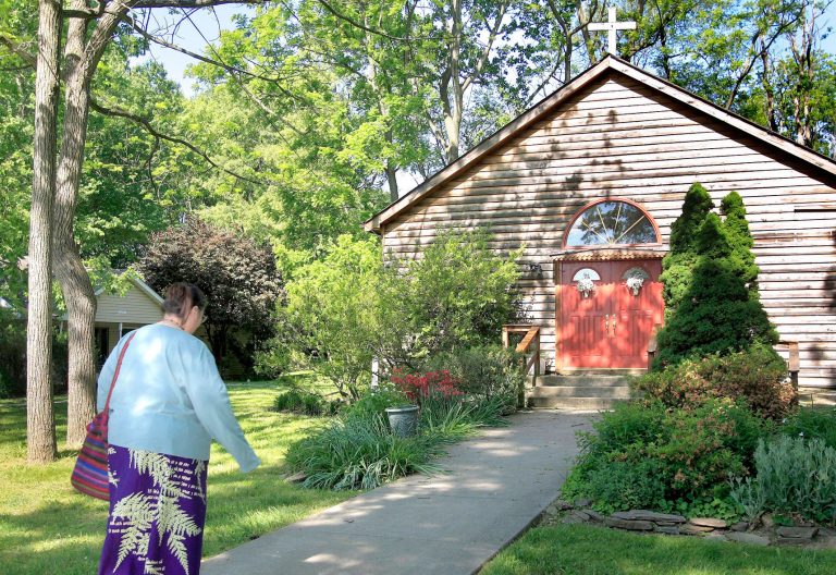 Una mujer se dirige a una capilla en medio del campo para orar