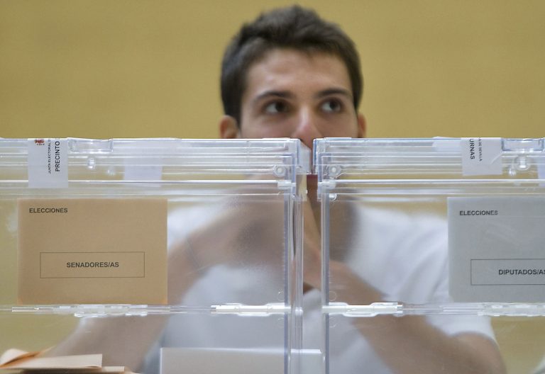 Un joven frente a las urnas en una mesa electoral