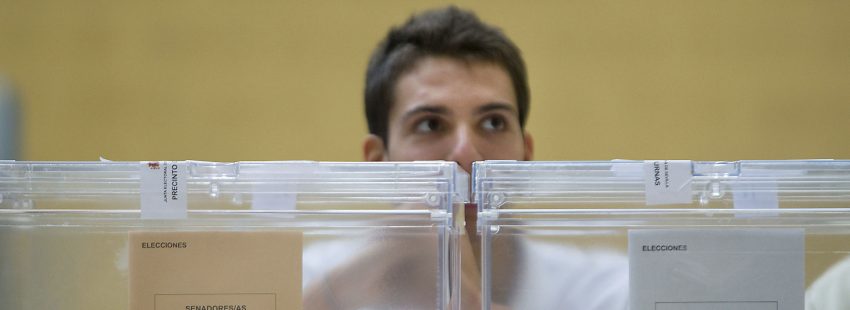 Un joven frente a las urnas en una mesa electoral