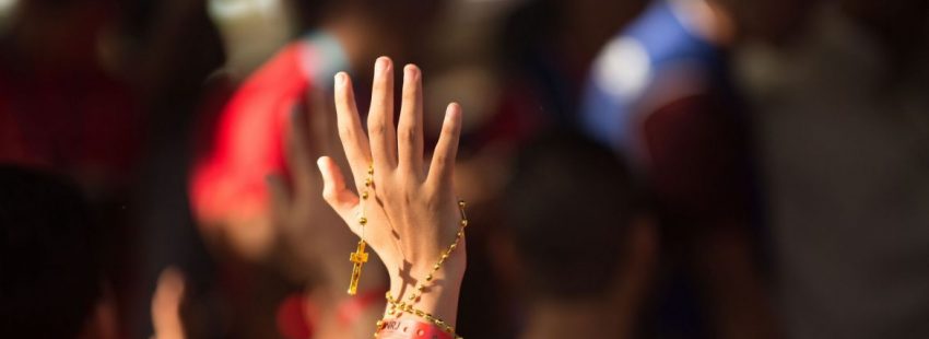 Una joven con un rosario en la mano