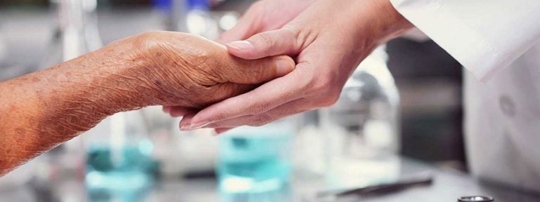 La mano de una enfermera toma la de un enfermo de Cuidados paliativos