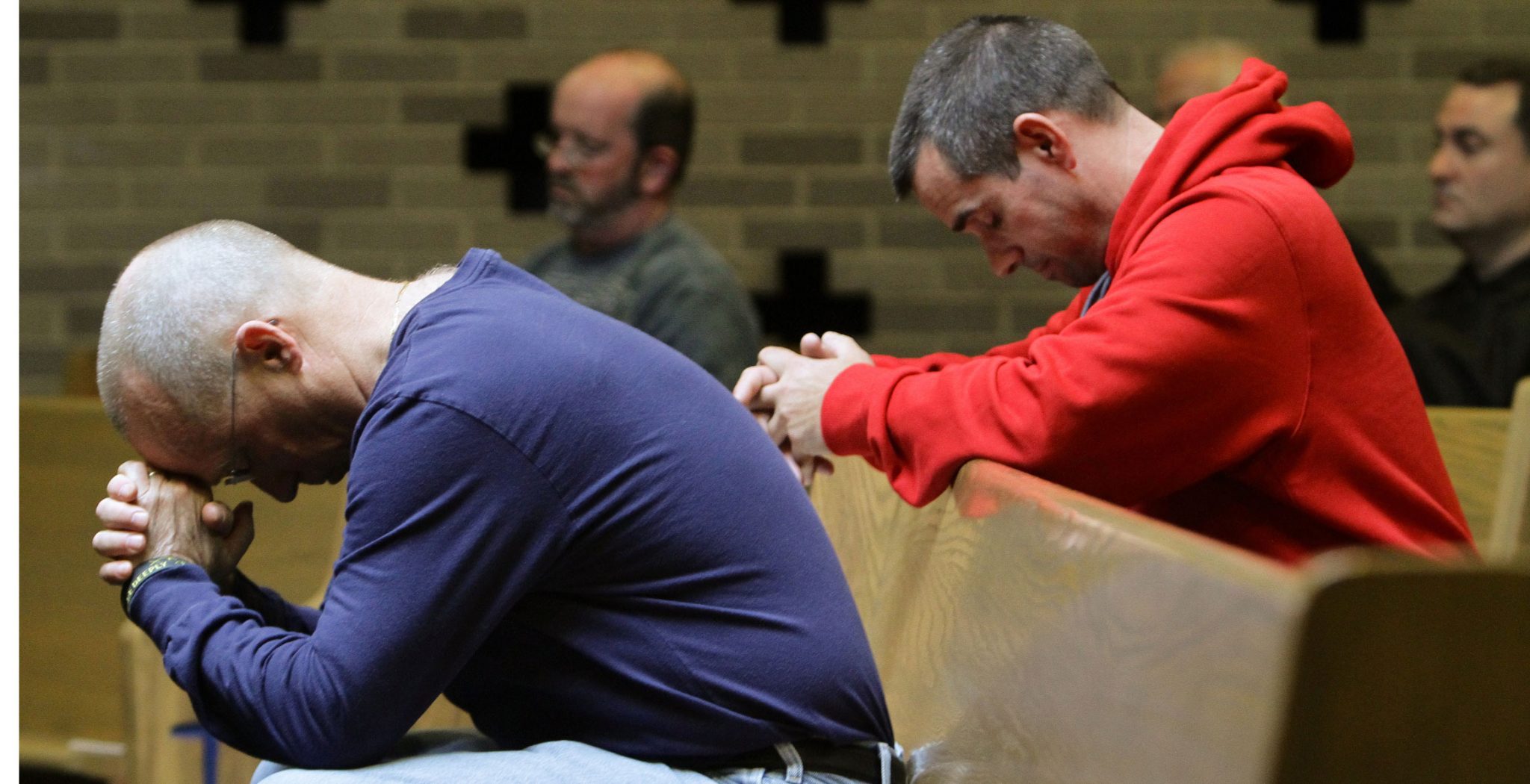 Varios adultos meditan/oran en los bancos de un templo