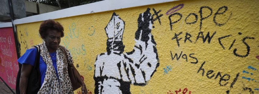 Una mujer, en una calle de Isla Mauricio, frente a un mural con un dibujo del Papa/EFE