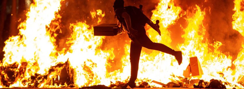 BARCELONA, 15/10/2019.- Un manifestante echa al fuego un cartón junto a la Delegación del