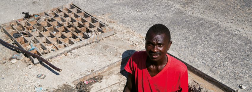 Un hombre limpiando las alcantarillas en las calles de Haití