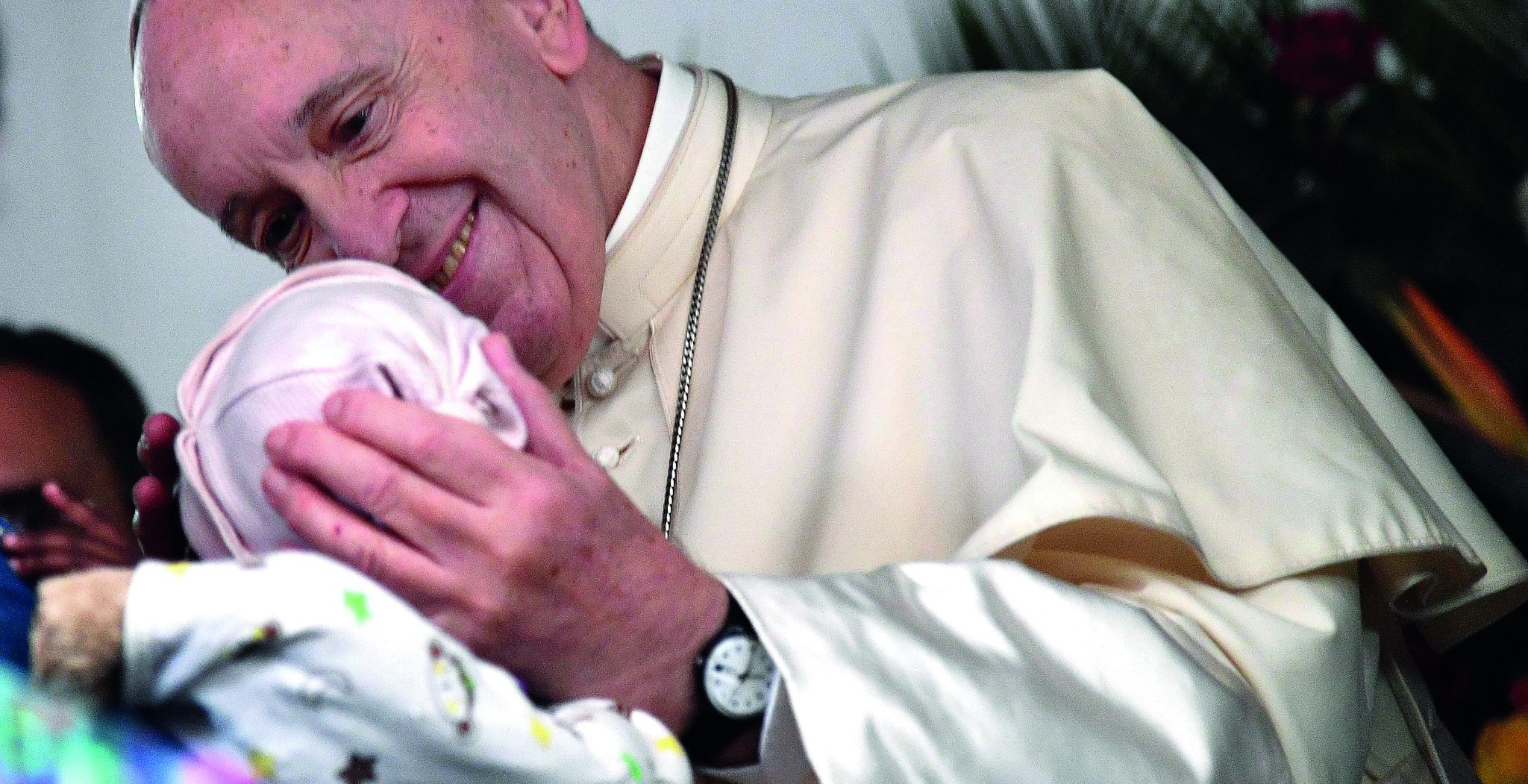Francisco acaricia el rostros de una bebé