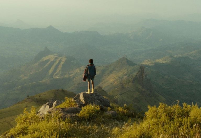 Un niño contempla el horizonte desde la cima de una montaña