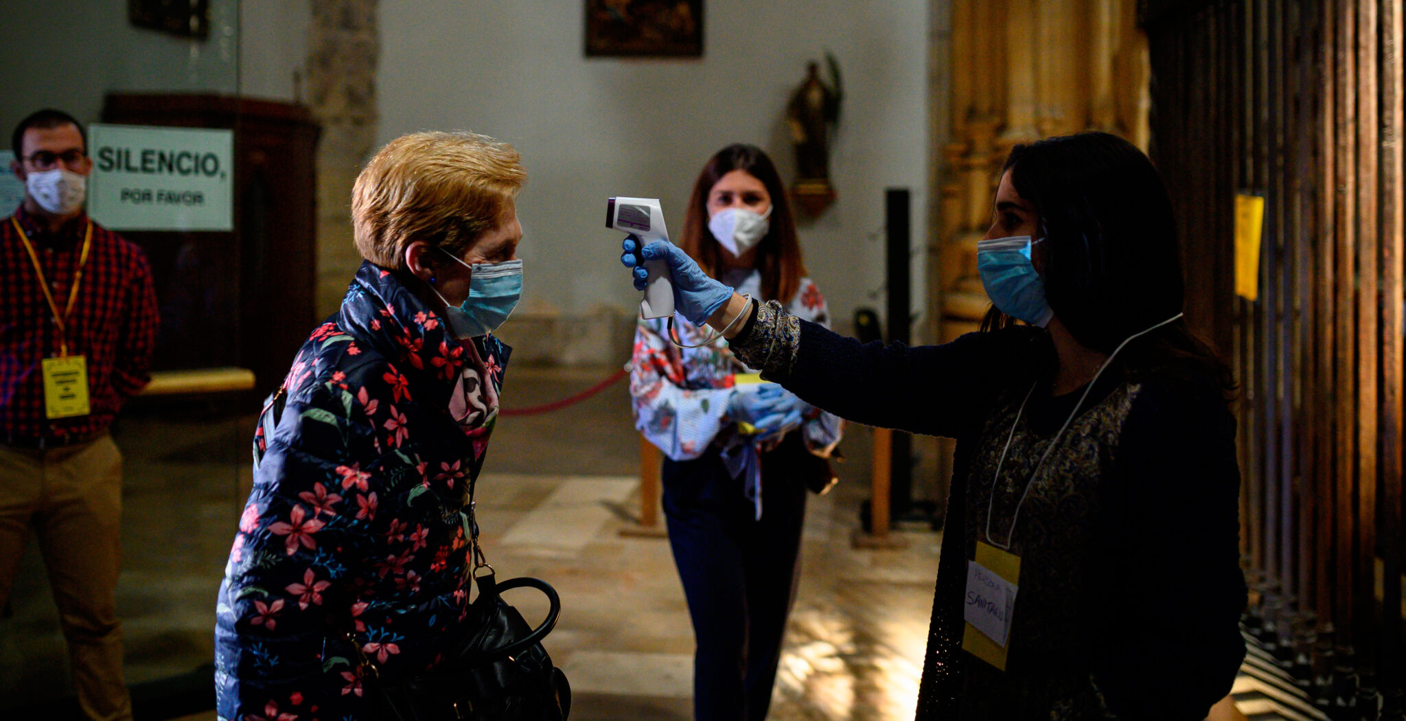 Una voluntaria toma la temperatura a los fieles que acuden a misa en la catedral de Alcalá de Henares