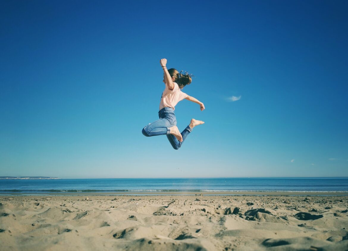 mujer saltando en la playa