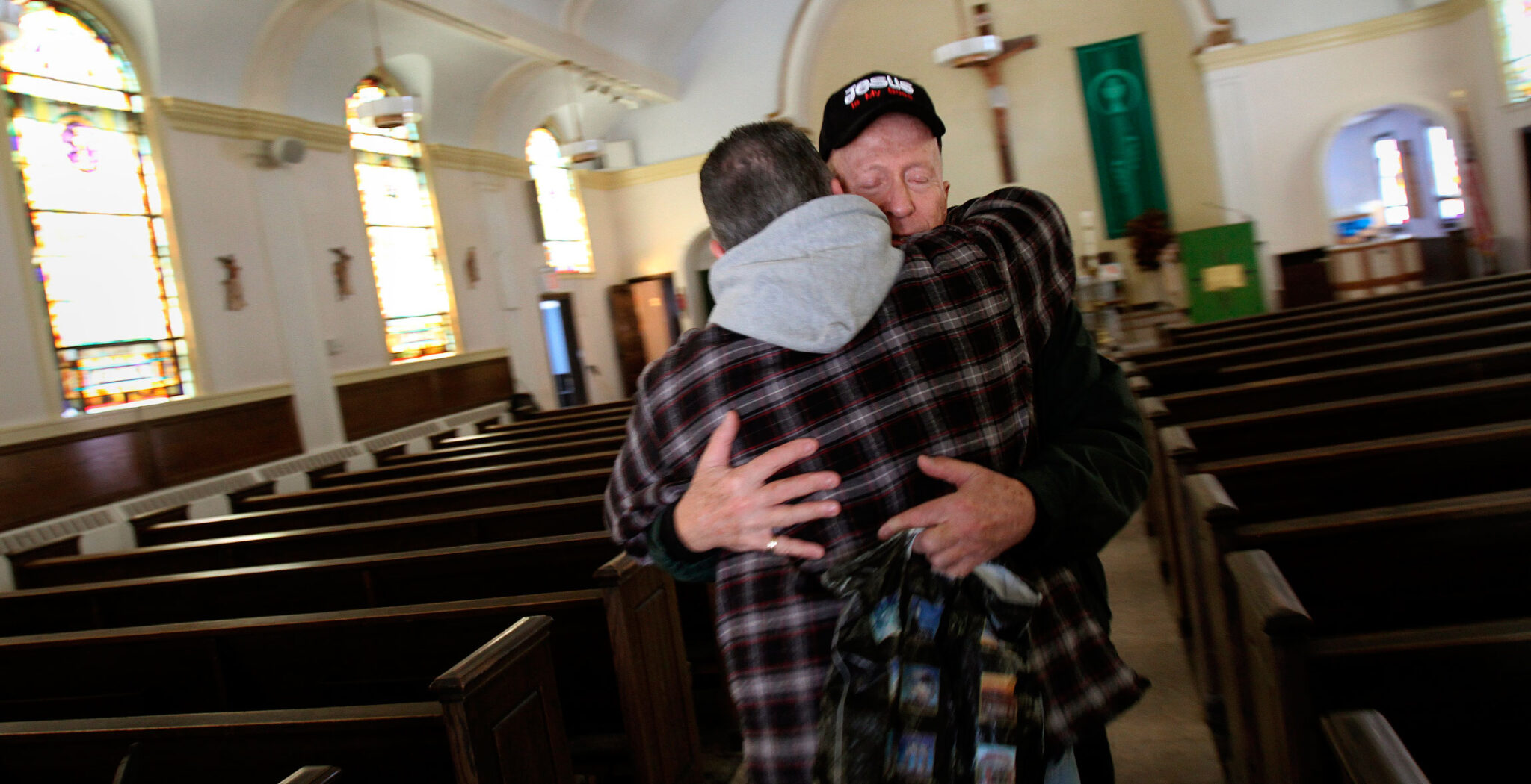 Un sacerdote acoge con una abrazo a un feligrés en medio de una iglesia vacía