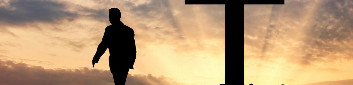 Un hombre alejándose de una gran cruz, al atardecer