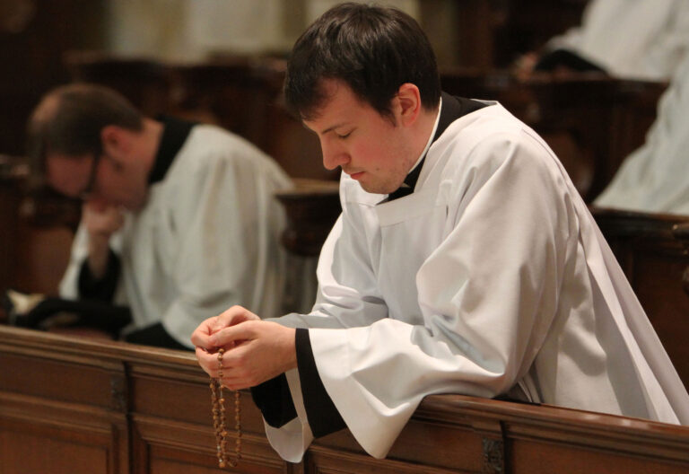 Seminarista en oración con un rosario entre las manos