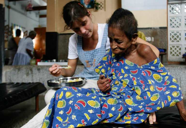 Una voluntaria atiende a una mujer en el centro de las Misioneras de la Caridad de Calcuta
