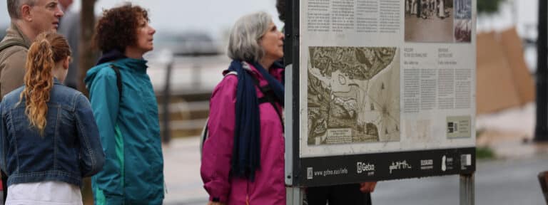 Visitantes en el País Vasco contemplan un cartel de información turística