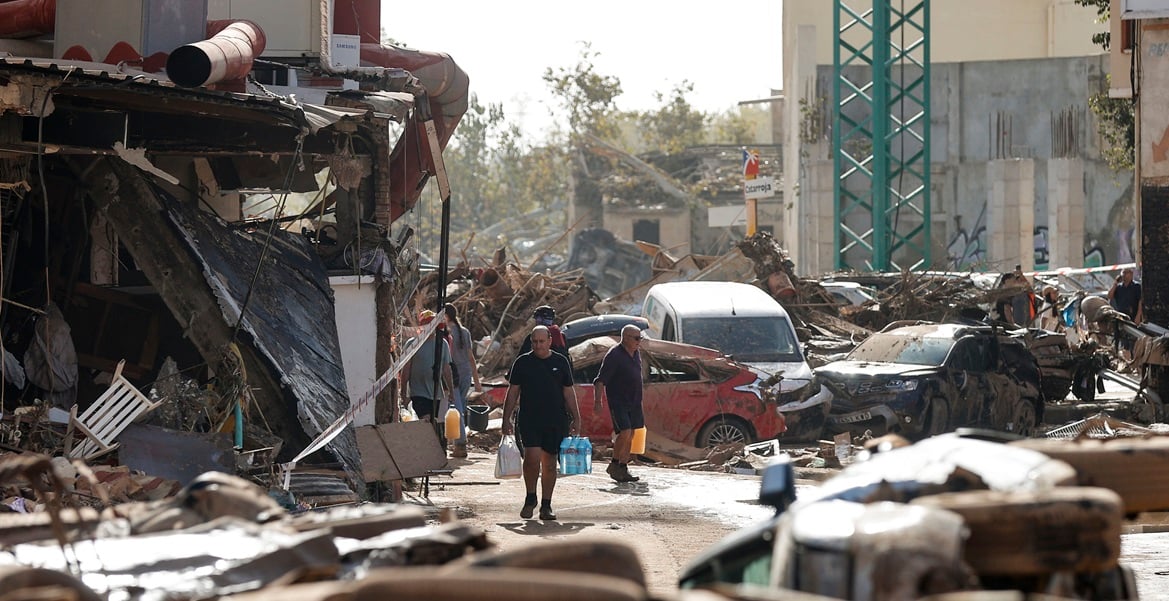 CATARROJA (VALENCIA), 31/10/2024.- Varias personas caminan entre el lodo acumulado en las calles a