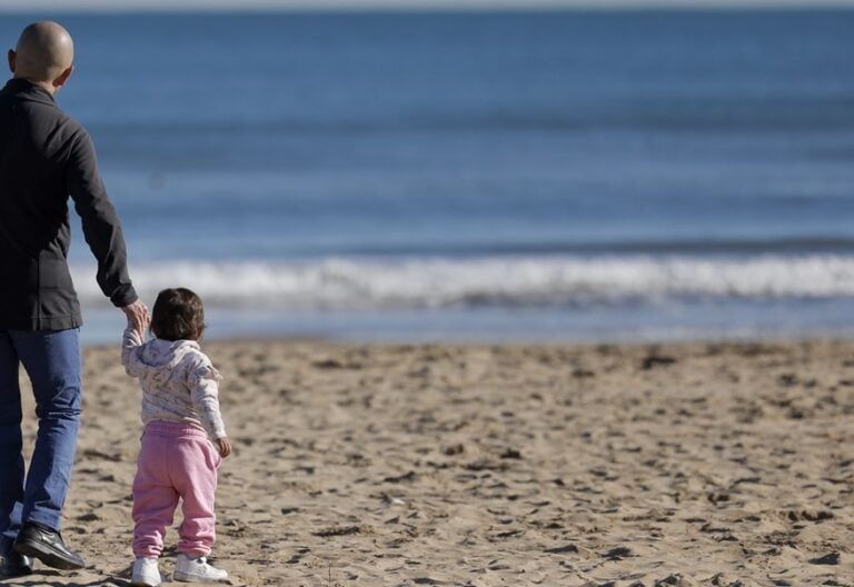 Un padre con su hija en una playa de Valencia