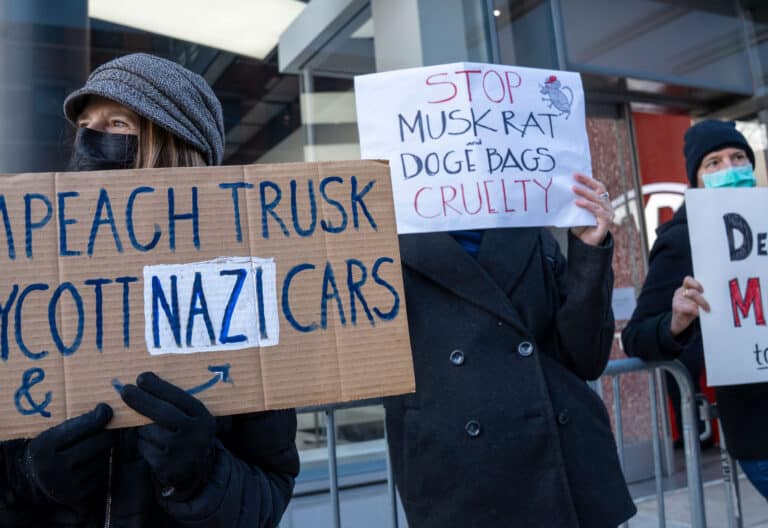 Una persona sostiene un cartel durante una manifestación este jueves, frente a un concesionario de automóviles Tesla en Manhattan (Estados Unidos).