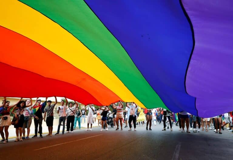 Personas sosteniendo una bandera en una marcha por el Día Internacional del Orgullo LGTBI, en La