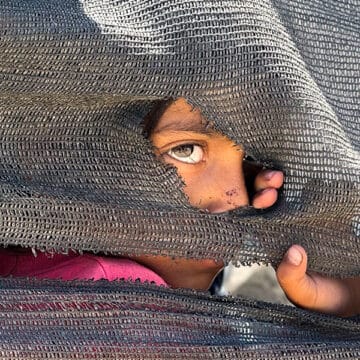 Una niña se asoma tras una tienda improvisada en el puerto en la Ciudad de Gaza