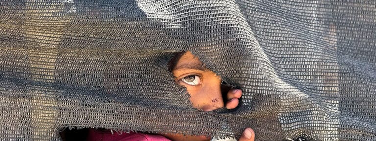 Una niña se asoma tras una tienda improvisada en el puerto en la Ciudad de Gaza